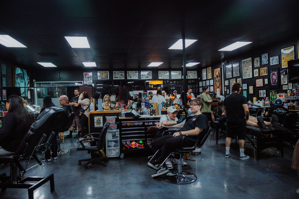 Interior of Golden Child Tattoo & Piercing Shop showing tattoo artists, piercers and clients engaged in live sessions at the Escondido, California studio.