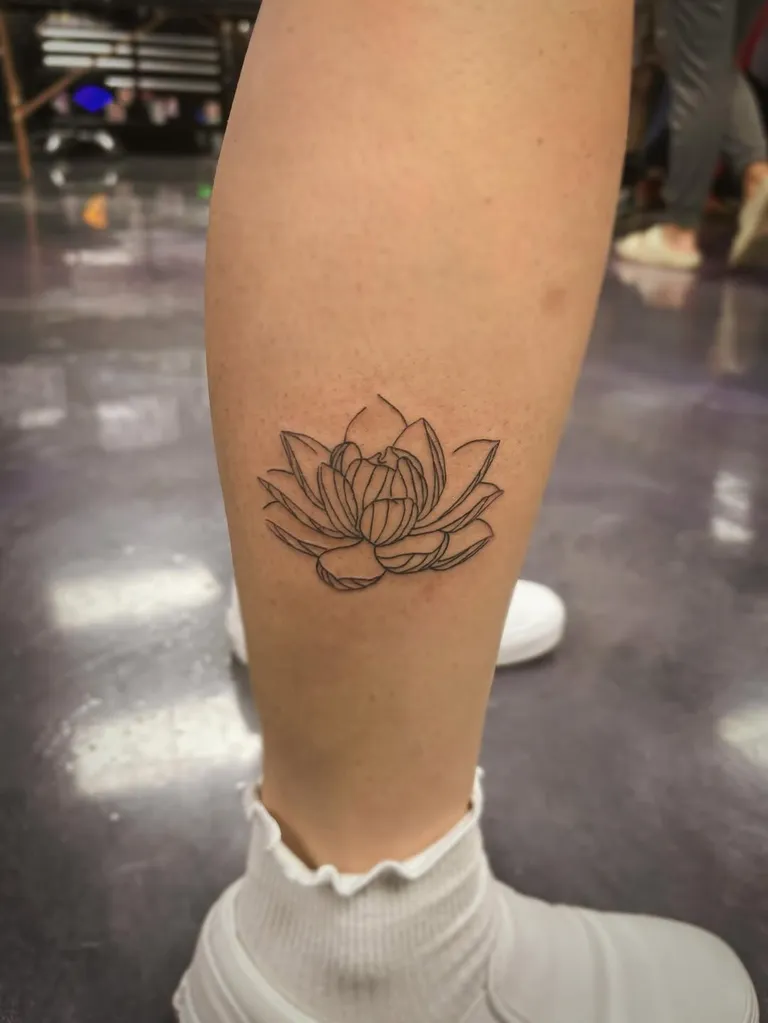 Fine line lotus flower tattoo on the calf by Melissa at Golden Child Tattoo in Escondido