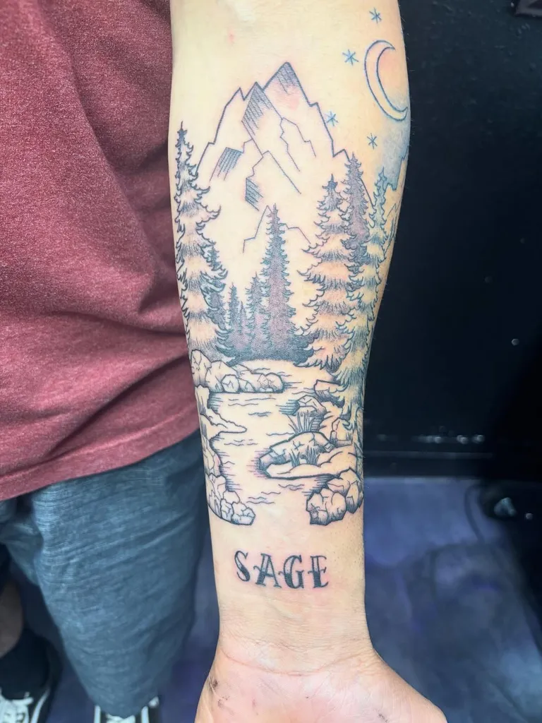 Mountain and forest landscape forearm tattoo with lettering by Melissa at Golden Child Tattoo in Escondido