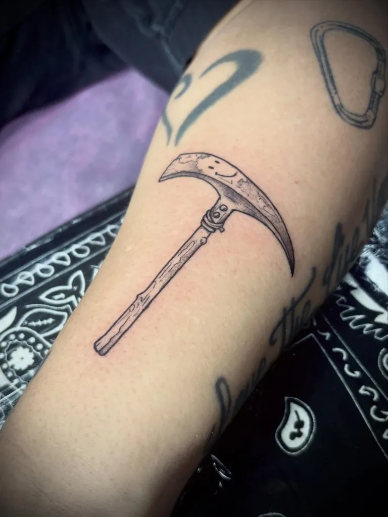 Pickaxe tattoo with a smiley face on the forearm by Melissa at Golden Child Tattoo in Escondido