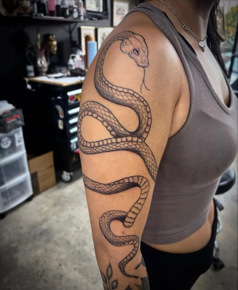 Snake tattoo wrapping the upper arm and shoulder by Melissa at Golden Child Tattoo in Escondido