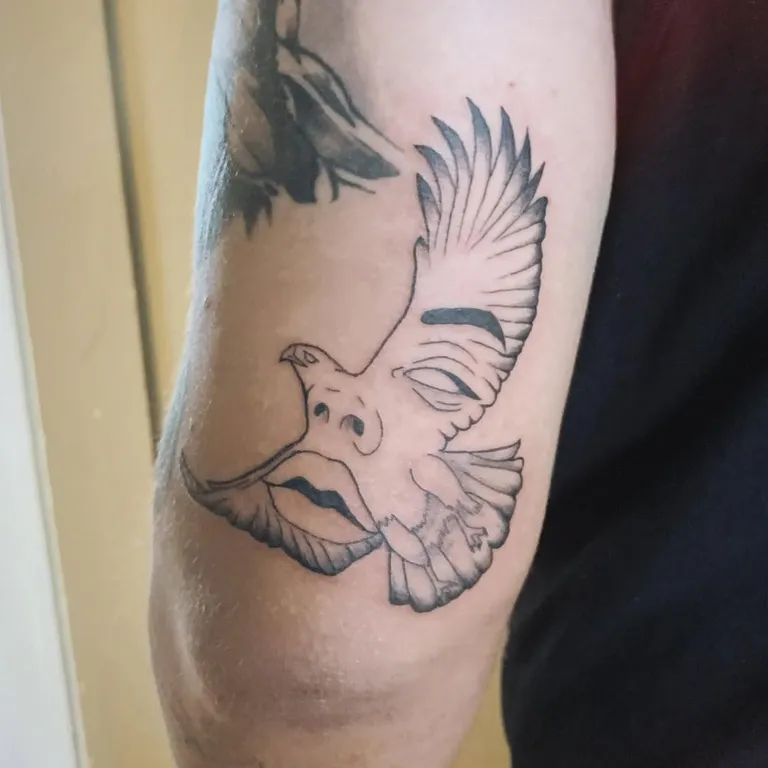 Hawk and face tattoo on the upper arm by Melissa at Golden Child Tattoo in Escondido