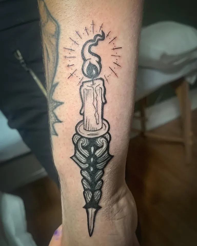 Lit candle on an ornate dagger, tattooed on the forearm by Melissa at Golden Child Tattoo in Escondido