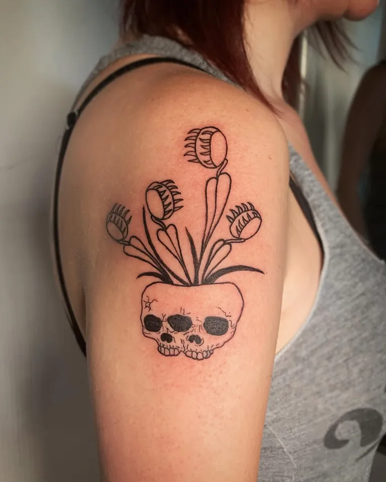 Venus flytrap growing from a skull planter, tattooed on the upper arm by Melissa at Golden Child Tattoo in Escondido