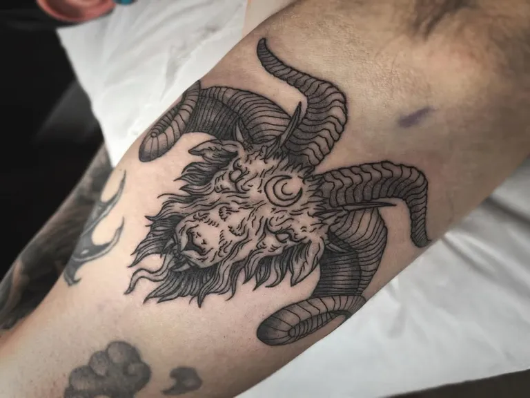 Goat head tattoo with curled horns on the arm by Melissa at Golden Child Tattoo in Escondido