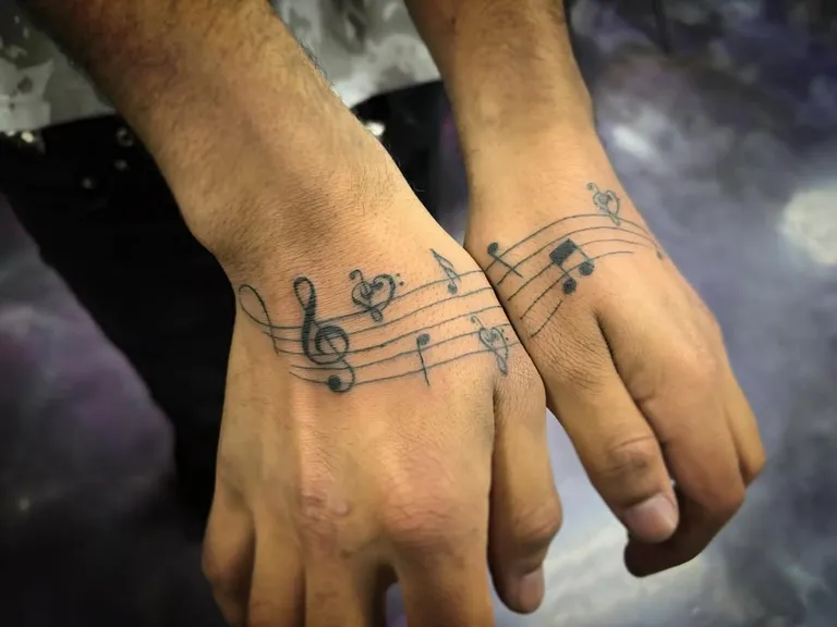 Music staff and notes tattoo across both hands by Melissa at Golden Child Tattoo in Escondido