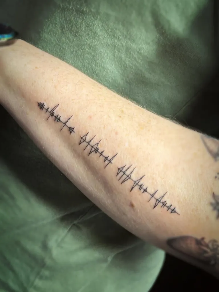 Fine line glyph script tattoo along the forearm by Melissa at Golden Child Tattoo in Escondido