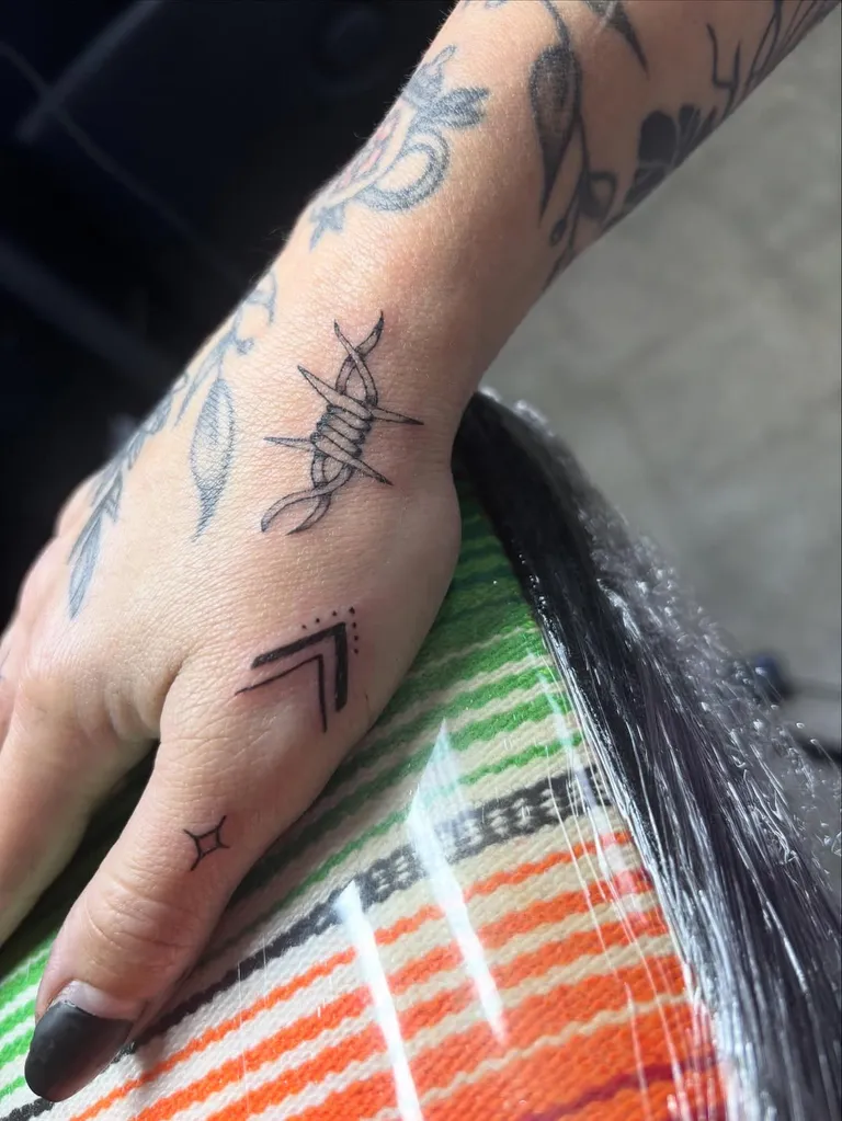 Small arrow and symbol tattoos on the side of the hand by Melissa at Golden Child Tattoo in Escondido