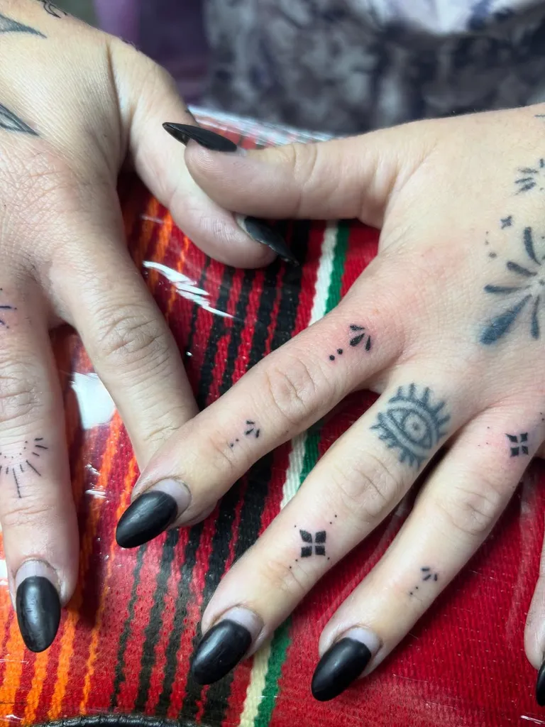 Small fine line finger and hand tattoos, including an eye, on both hands by Melissa at Golden Child Tattoo in Escondido