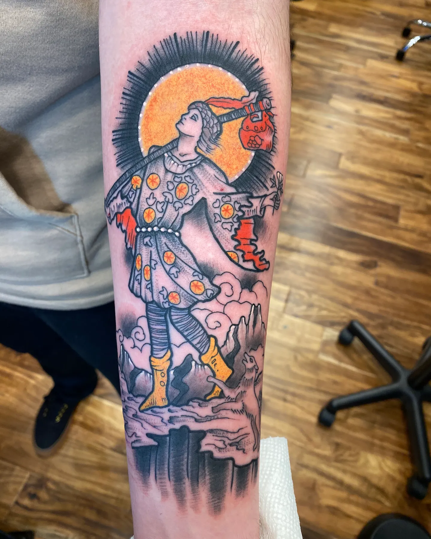 Color tattoo of a figure in a patterned robe against an orange sun by Mathias Moretti at Golden Child Tattoo in Escondido