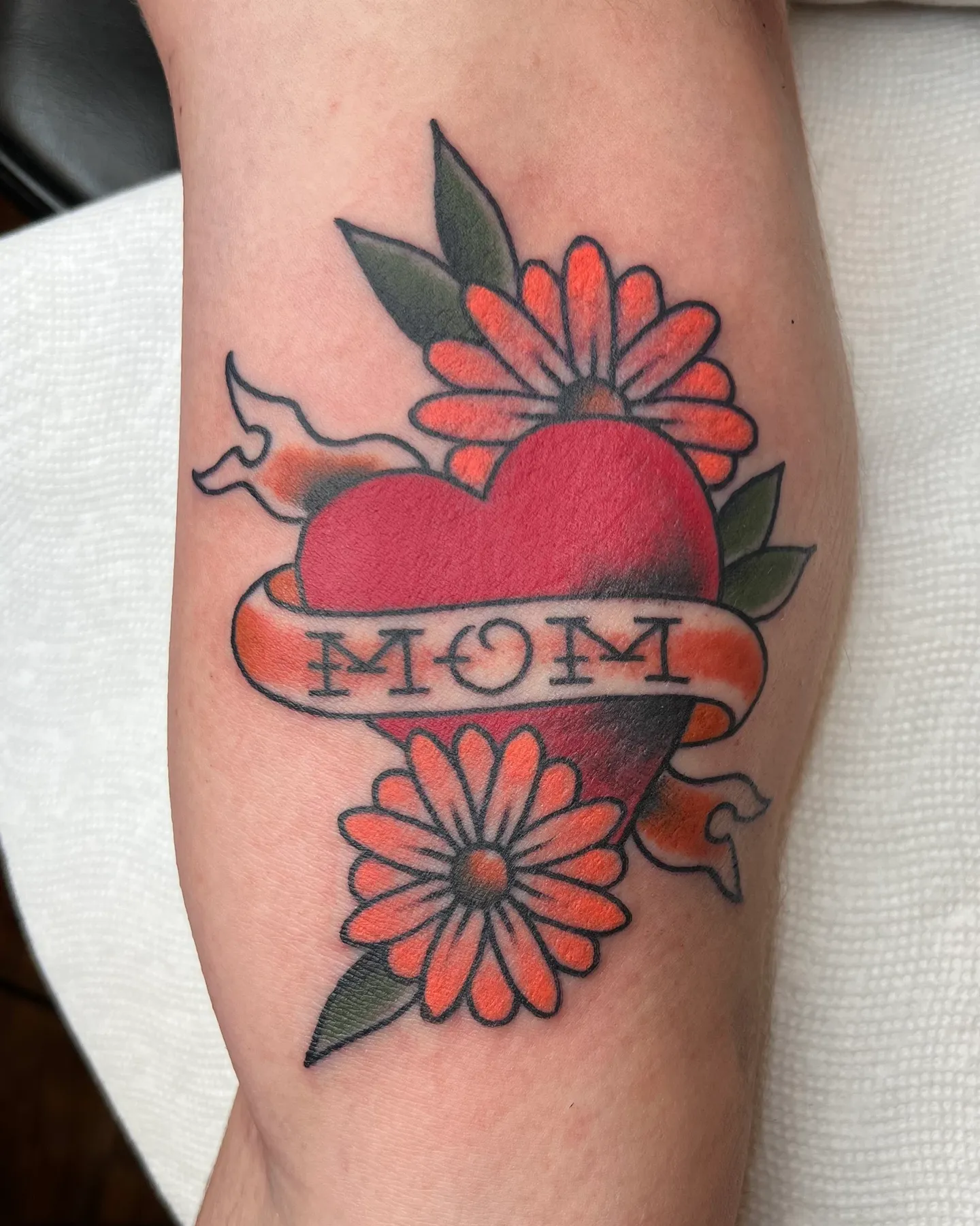 American traditional heart tattoo with a MOM banner and red flowers by Mathias Moretti at Golden Child Tattoo in Escondido