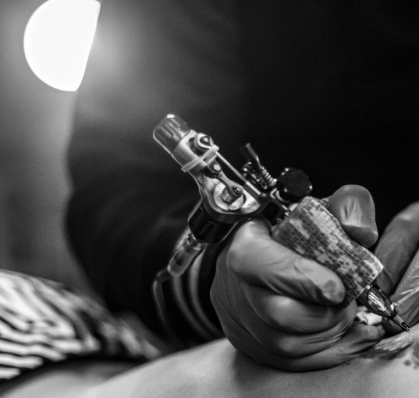 Golden Child tattoo artist at work with a rotary machine