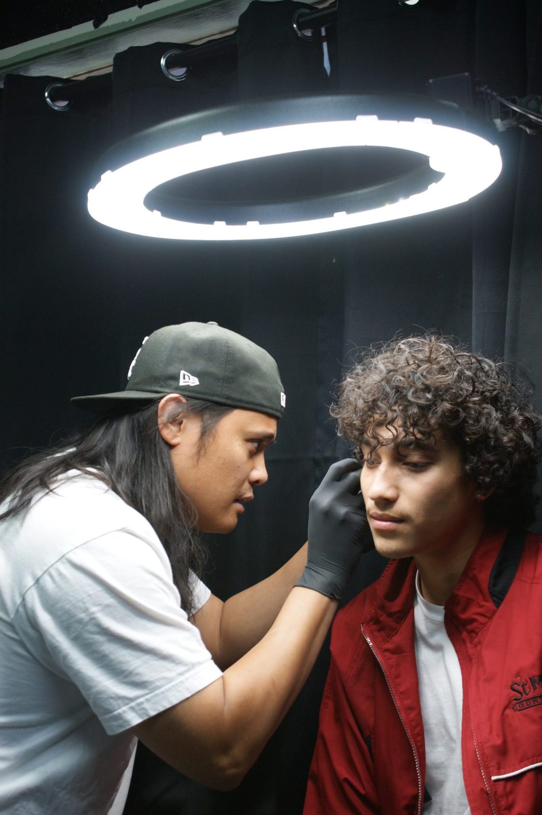 An ear-piercing procedure under a studio task light at Golden Child Tattoo and Piercing in Escondido