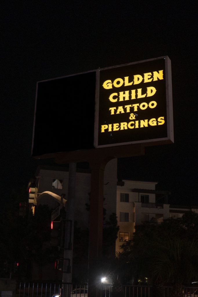 Golden Child Tattoo & Piercing storefront sign lit up at night in Escondido