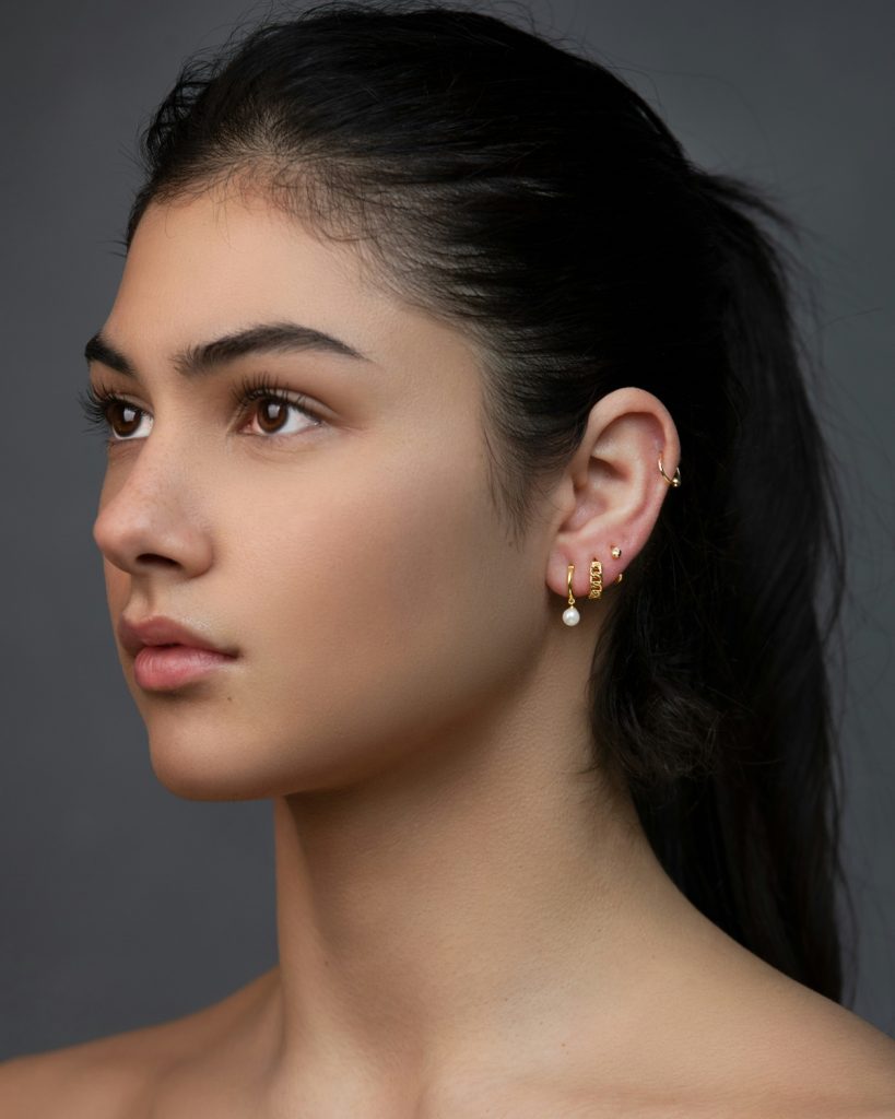 Multiple types of ear piercings shown on a woman modeling a custom ear styling approach