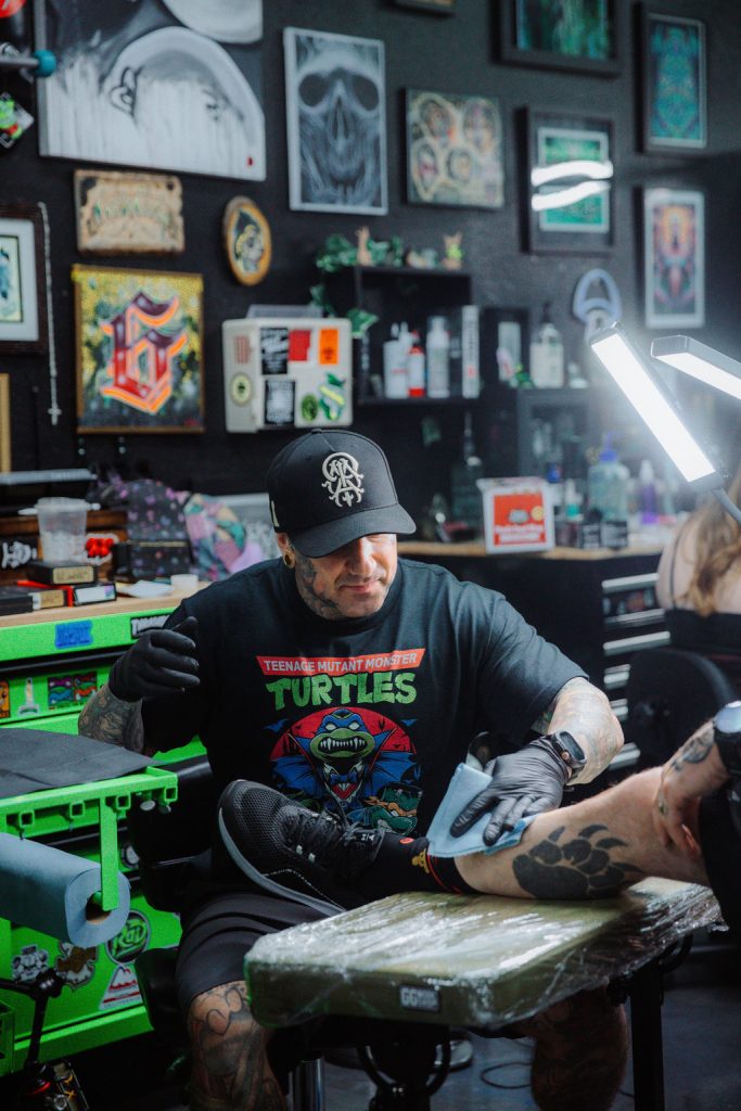 Sixer, founder of Golden Child, focuses on a black and gray realism tattoo during a client session.