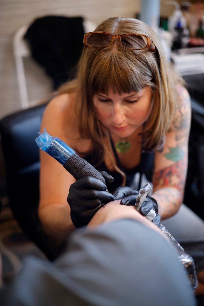 Olivia Thompson tattooing at Golden Child Tattoo in Escondido